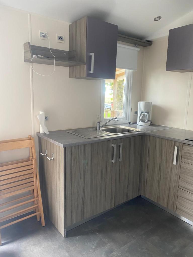 une cuisine avec des armoires en bois et un évier dans l'établissement Mobil home en Vendée, à Angles