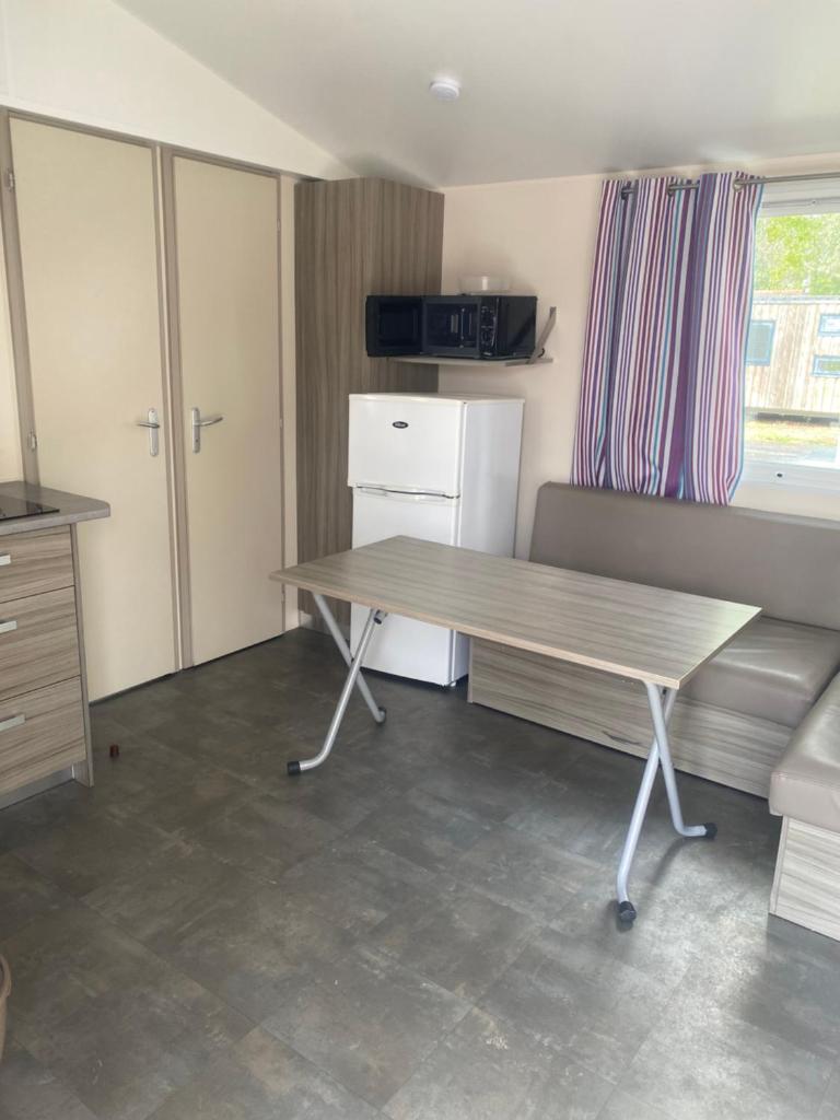Cette chambre dispose d'une table, d'un réfrigérateur et d'un canapé. dans l'établissement Mobil home en Vendée, à Angles