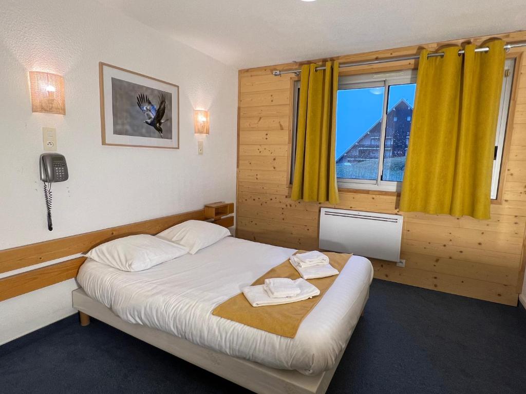 - une chambre avec un lit et une fenêtre avec des rideaux jaunes dans l'établissement Le Balcon des Ecrins, à Réallon