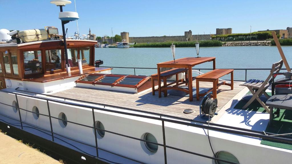 - un bateau avec une table et des chaises sur le pont dans l'établissement Peniche Saul Nomad, à Aigues-Mortes