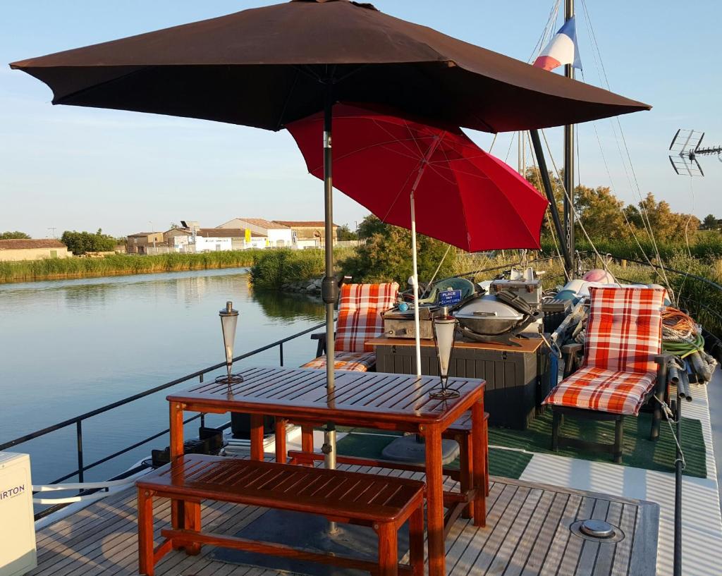 - une table et des chaises sur un bateau avec un parasol dans l'établissement Peniche Saul Nomad, à Aigues-Mortes
