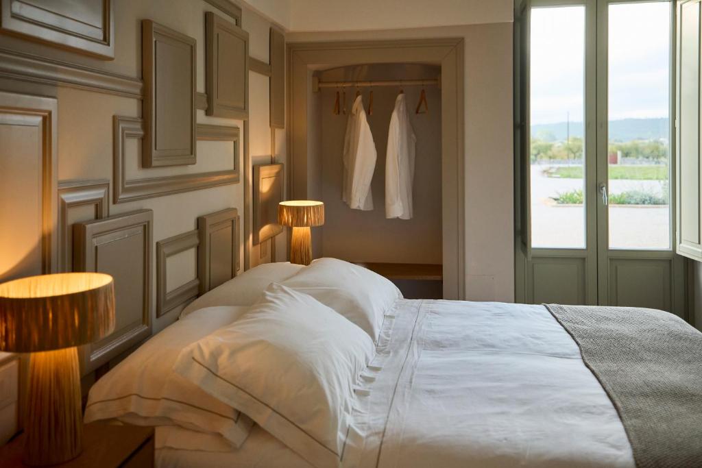 - une chambre avec un lit blanc, deux lampes et une fenêtre dans l'établissement Tenuta Giotta, à Castellana Grotte