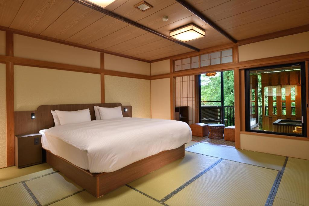 une chambre avec un grand lit et un balcon dans l'établissement Yunogo Bishunkaku, à Mimasaka