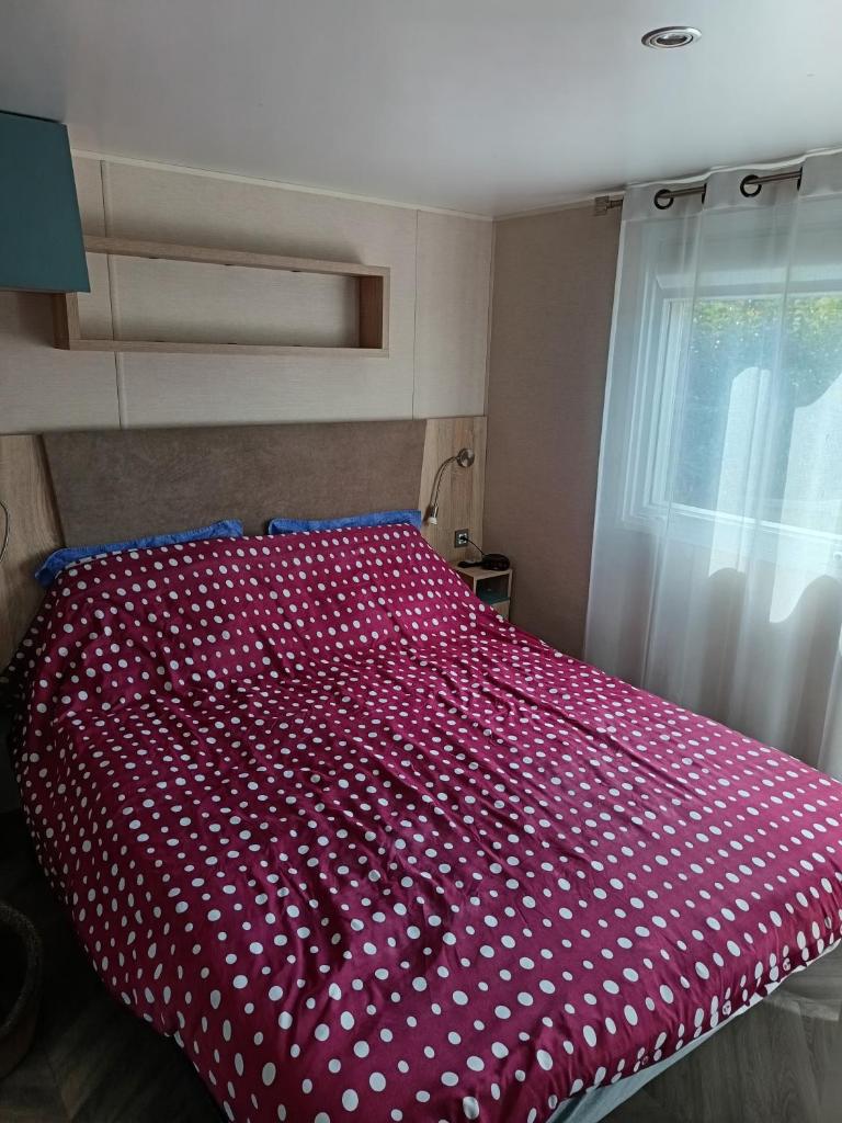un lit avec un couvre-lit rouge à pois blancs dans l'établissement Le petit paradis, à Fréjus