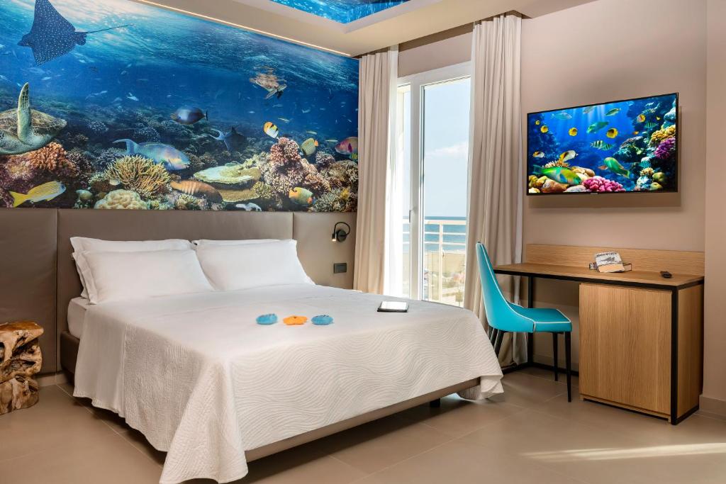une chambre avec un lit, un bureau et un aquarium dans l'établissement Hotel Adlon - FRONTE MARE, à Riccione