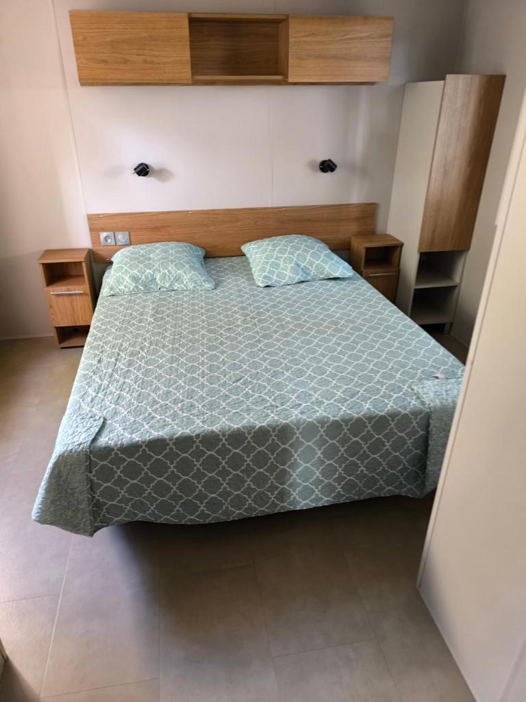 une chambre avec un lit avec une couette bleue dans l'établissement MH 201 AGREABLE et tout ÉQUIPÉ 2CH dont suite parentale et 2sdb avec vue sur foret dans camping 4 étoiles, à Saint-Julien-en-Born