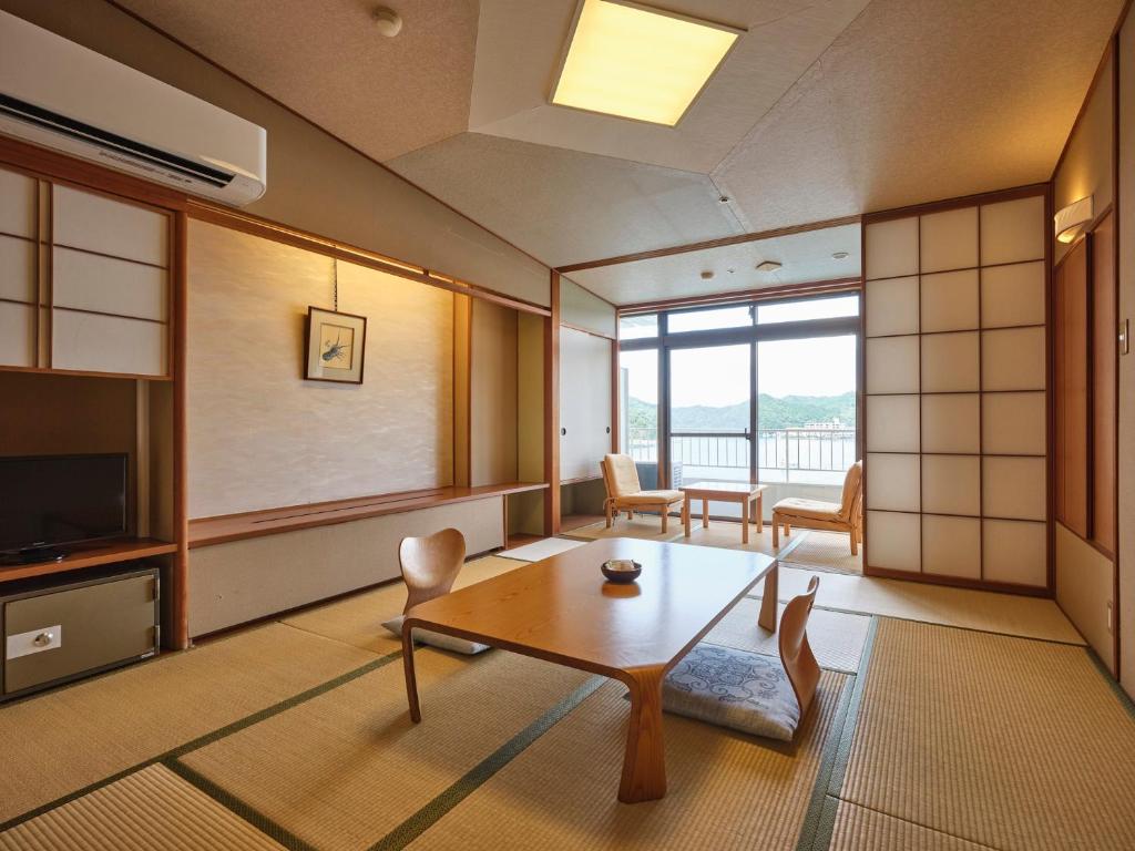 un salon avec une table et une télévision dans l'établissement Hotel Urashima, à Katsuura