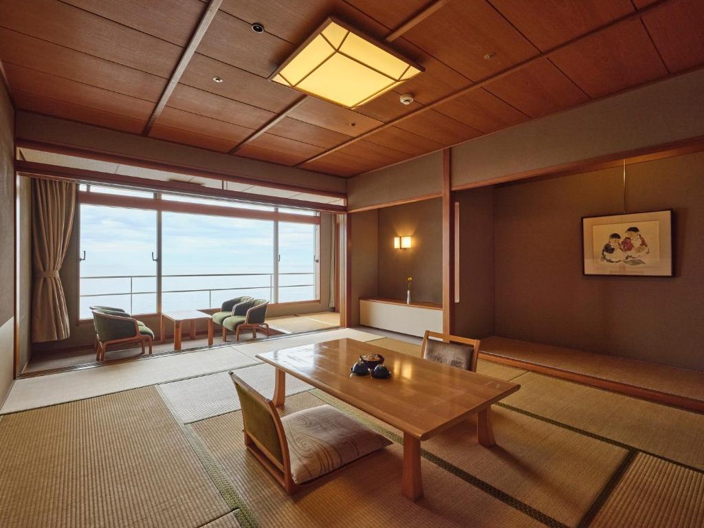 un salon avec une table et une grande fenêtre dans l'établissement Hotel Urashima, à Katsuura 37 autres photos