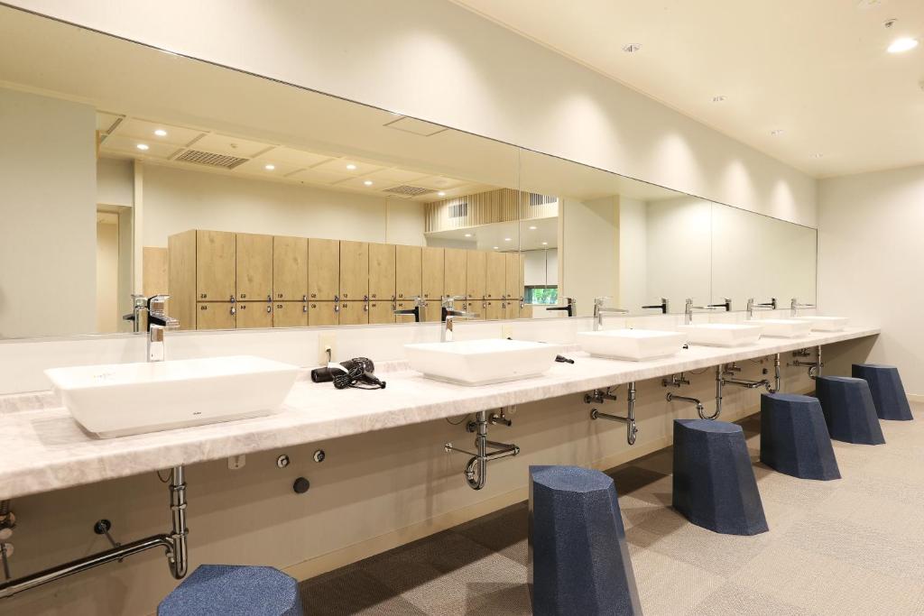 La salle de bains est pourvue d'une rangée de lavabos et de miroirs. dans l'établissement Hotel Sakurai, à Kusatsu