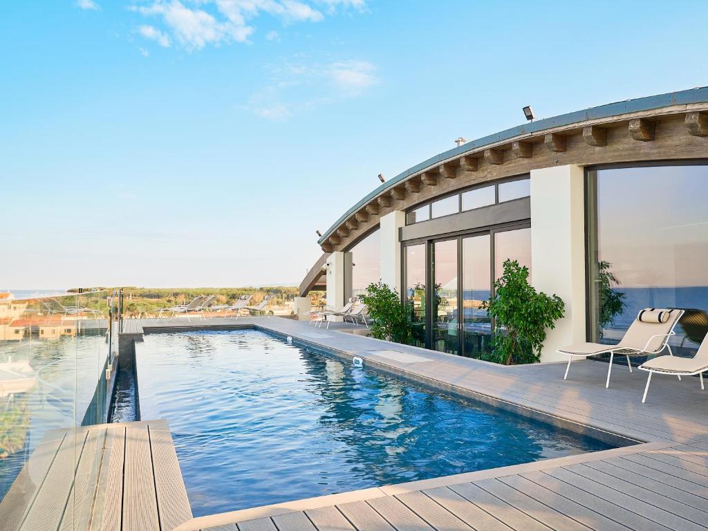 une piscine avec deux chaises et une maison dans l'établissement Palace Lido Hotel & Suites, à Marina di Cecina