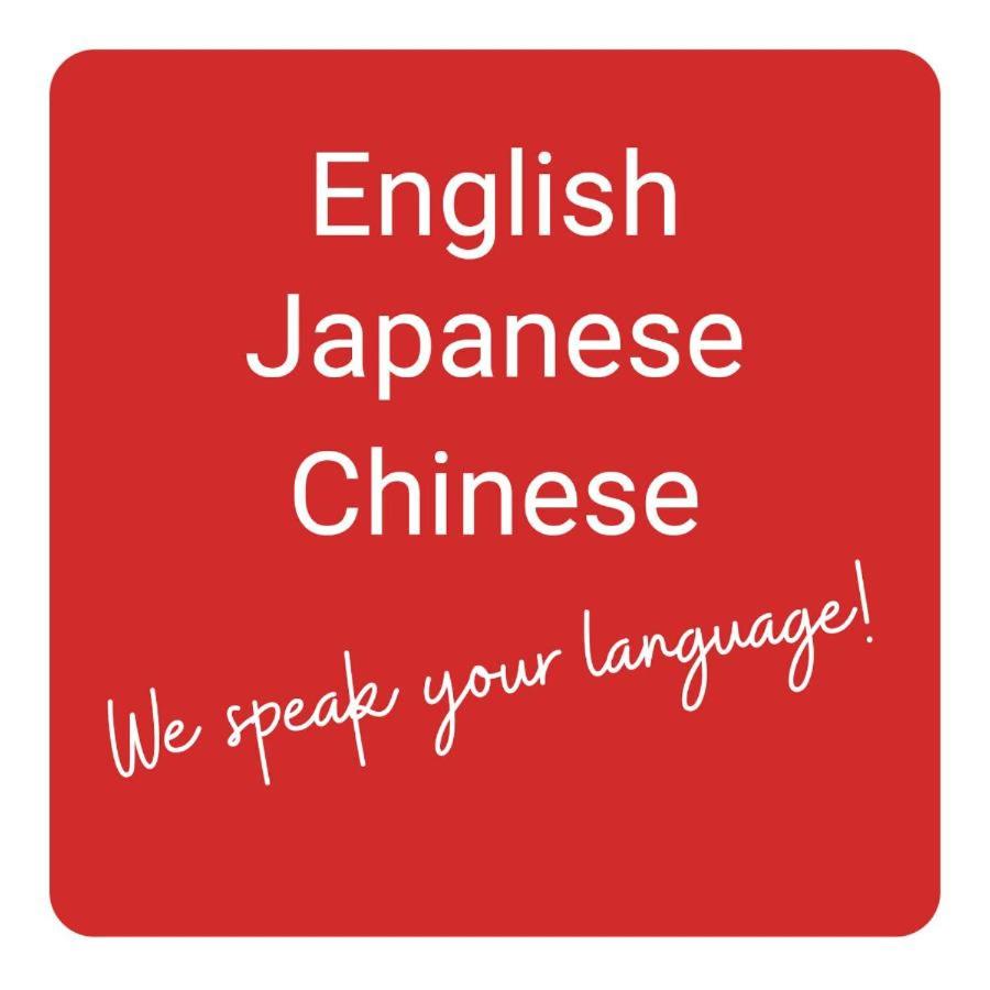 Un panneau rouge qui dit anglais japonais chinois nous parlons votre langue dans l'établissement Resort Project Myoko Kogen Hot Spring, à Myōkō