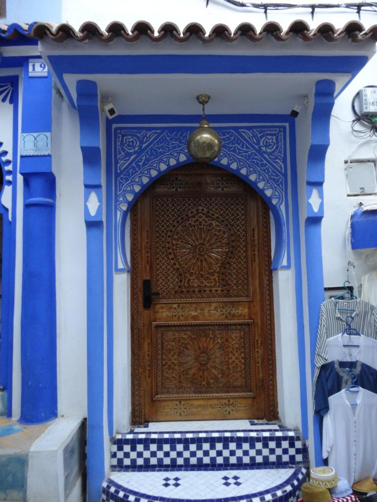 une porte en bois sur un bâtiment bleu et blanc dans l'établissement Palacio Del Sol, à Chefchaouen