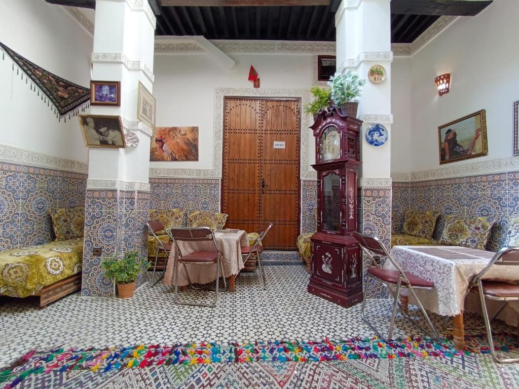 - un salon avec une table et une horloge grand-père dans l'établissement Riad Basma Fes - Tranquil Getaway, à Fès