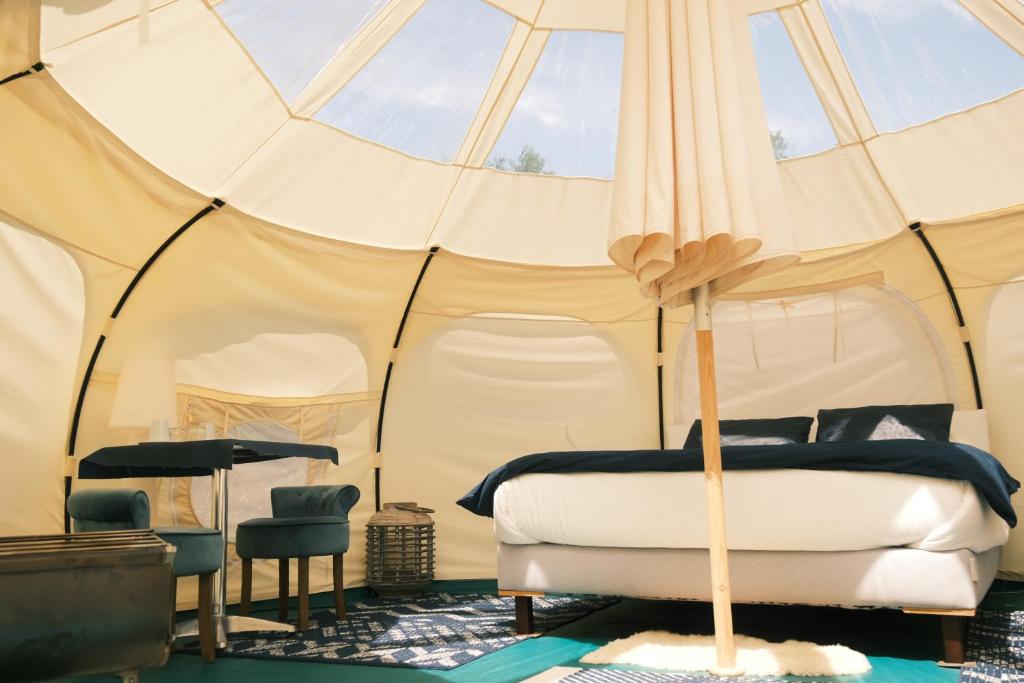 une chambre avec un lit dans une tente dans l'établissement domaine des butineuses, à Marchainville