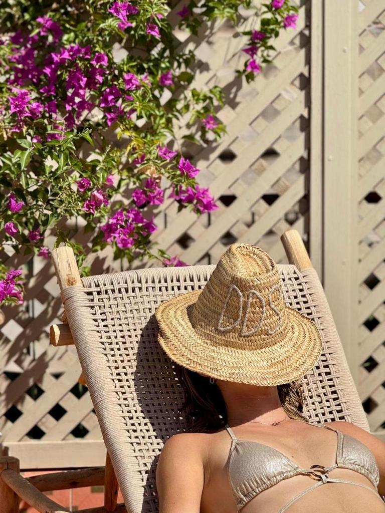 une femme dans un chapeau de paille assise dans une chaise en osier dans l'établissement Riad Dollar Des Sables & Spa, à Marrakech