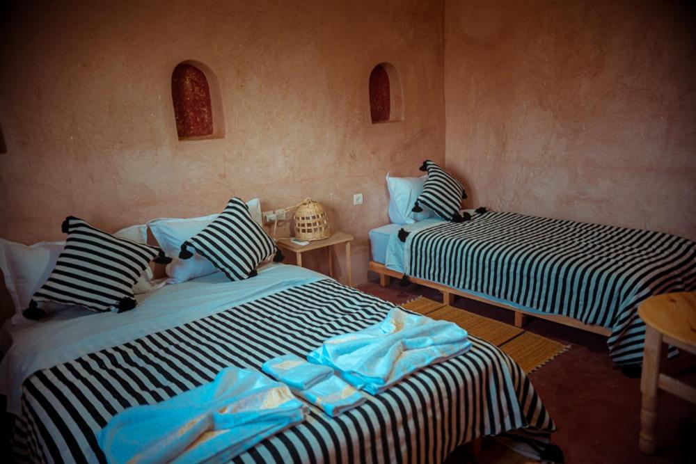 une chambre avec deux lits et une table dans l'établissement Riad Zaytoune, à Ouarzazate