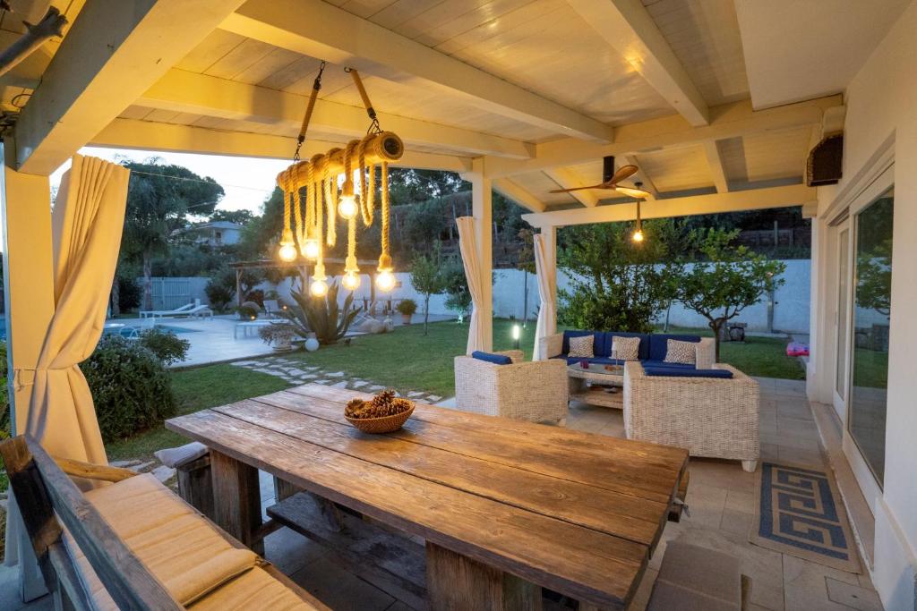 un patio avec une table et des chaises en bois dans l'établissement Villa Michaela con piscina privata e vista mare, à Capo Vaticano