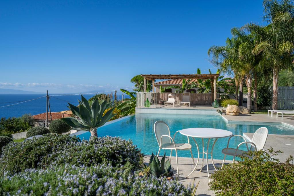 - une piscine avec une table et des chaises et l'océan dans l'établissement Villa Michaela con piscina privata e vista mare, à Capo Vaticano