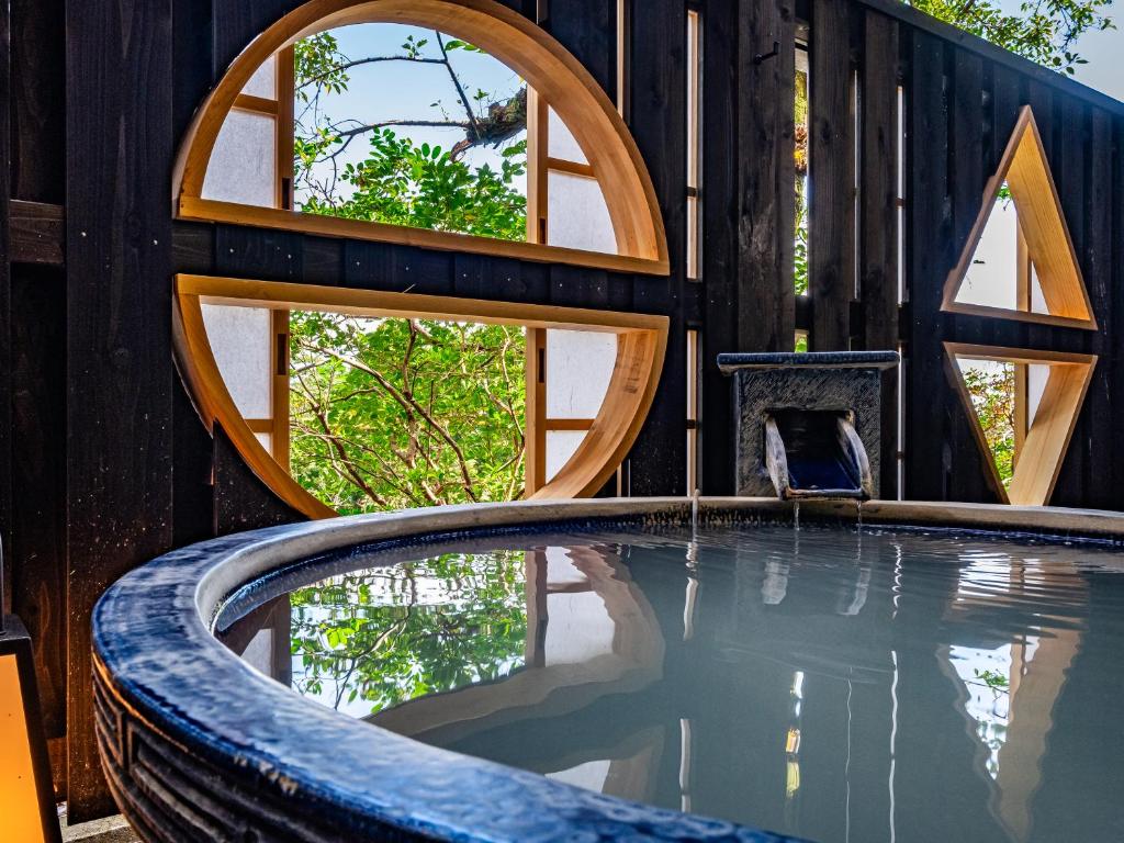 une maison avec une piscine dotée de fenêtres circulaires dans l'établissement Nagominoyado Hanagokoro - Reopening in Mar 2024, à Hakone