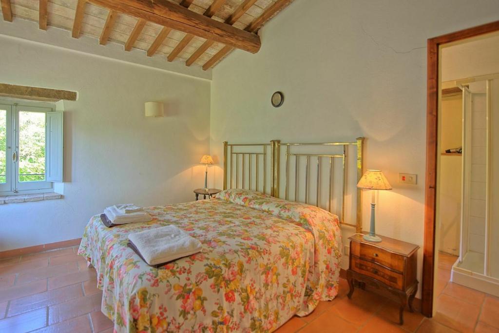une chambre avec un lit et une table avec une lampe dans l'établissement Villa Gualchiere by PosarelliVillas, à San Casciano dei Bagni