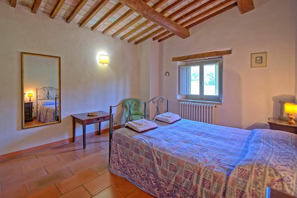 une chambre avec un lit, une table et un miroir dans l'établissement Villa Gualchiere by PosarelliVillas, à San Casciano dei Bagni