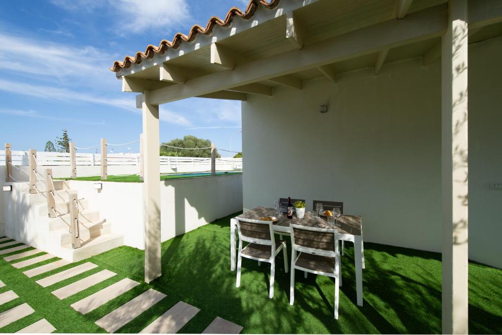 un patio avec une table et des chaises sous une pergola dans l'établissement Villa Lux, à San Vito Lo Capo
