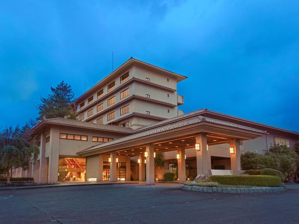 un grand bâtiment avec un parking devant dans l'établissement Ooedo Onsen Monogatari Premium Seiunkaku, à Awara