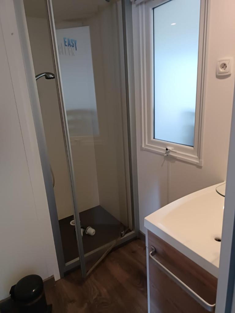 une salle de bain avec une douche, un lavabo et un miroir dans l'établissement MH F52 Camping Bois Masson, à Saint-Jean-de-Monts