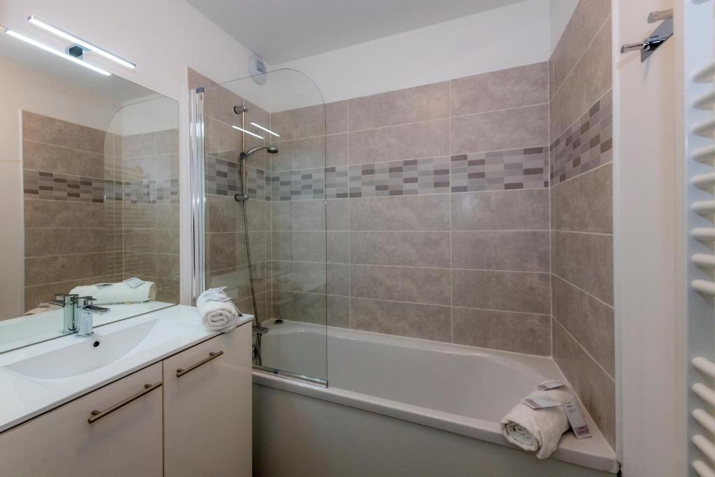une salle de bain avec une baignoire, un lavabo et une douche dans l'établissement Goélia Les Chalets des Pistes, à Combloux