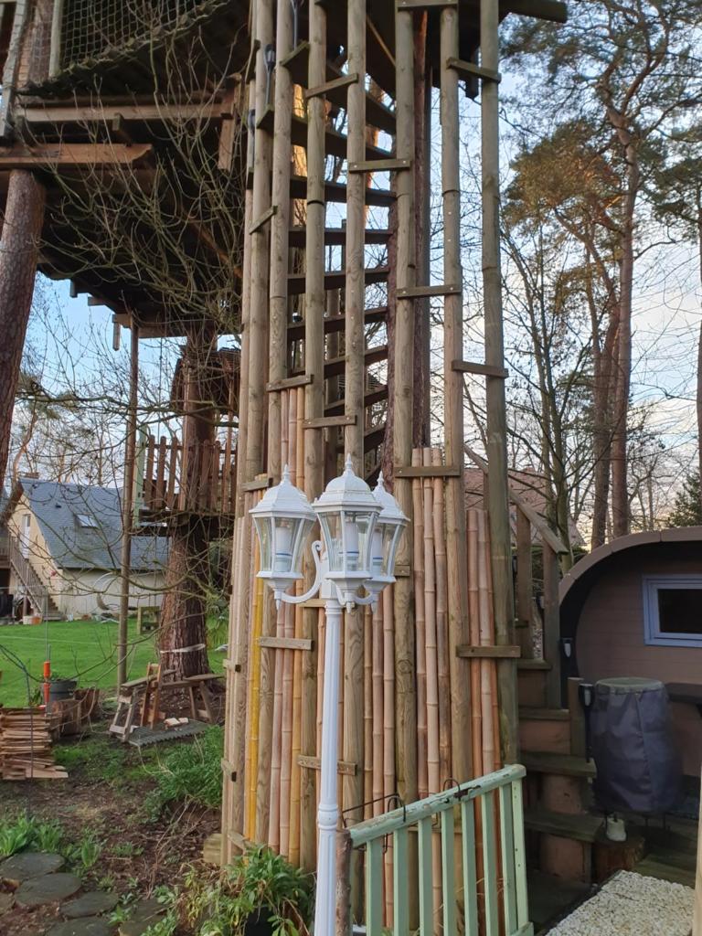 une lumière sur le côté d'un bâtiment en bois dans l'établissement Cabane dans les arbres, à Beaumontel 4 autres photos
