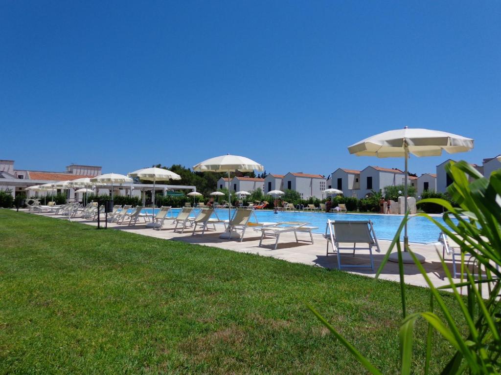 un groupe de chaises et de parasols à côté d'une piscine dans l'établissement Residence Blu Mare, à Otrante