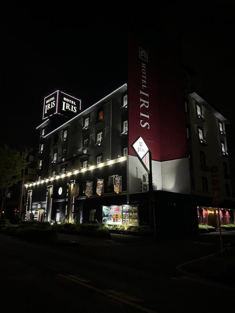 Un grand bâtiment avec des lumières allumées la nuit dans l'établissement Hotel IRIS -アイリス-, à Osaka