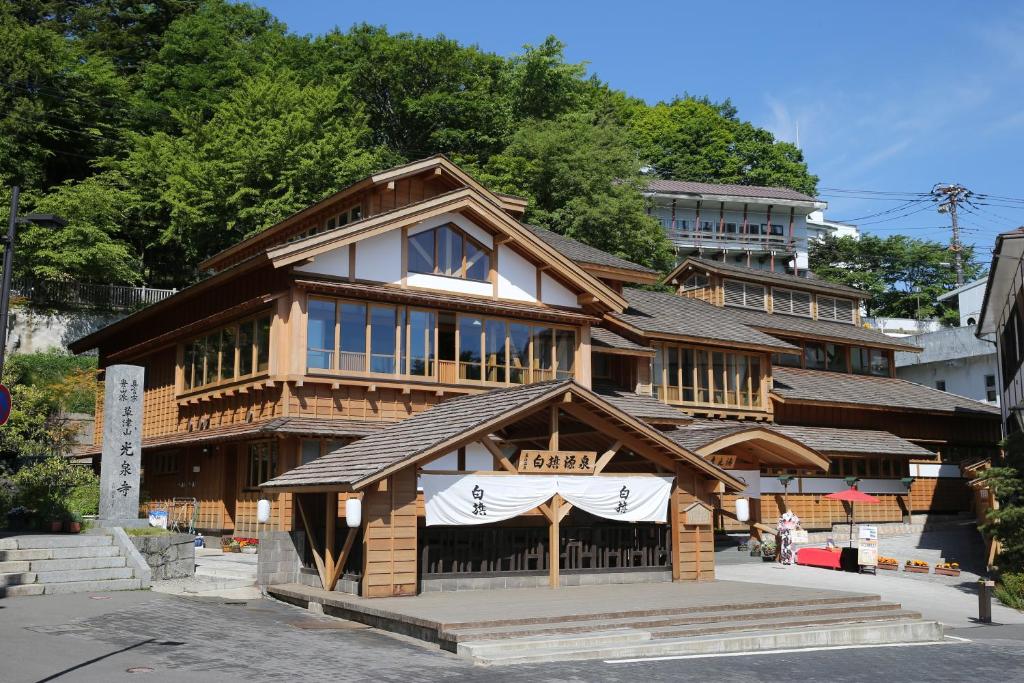 un bâtiment en bois avec un panneau en face de celui-ci dans l'établissement Hotel Sakurai, à Kusatsu
