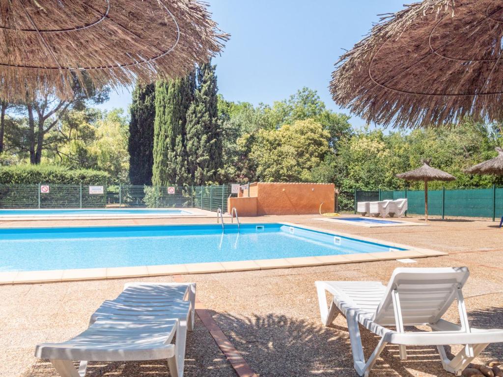 une piscine avec deux chaises et un parasol dans l'établissement Camping de la Chapelette, à Saint-Martin-de-Crau