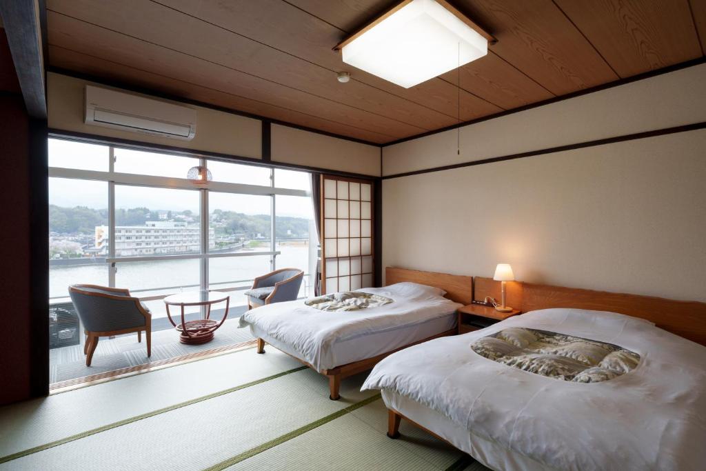 une chambre avec deux lits et une grande fenêtre dans l'établissement Hita Onsen Kizantei Hotel, à Hita