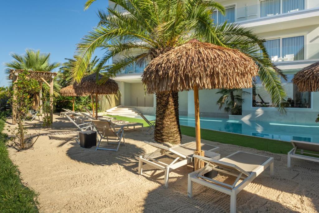 un groupe de chaises et de parasols à côté d'un complexe hôtelier dans l'établissement AQA Palace, à Caorle
