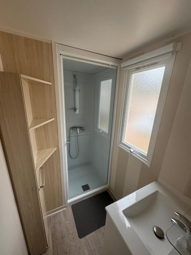 une salle de bain avec une douche, un lavabo et un miroir dans l'établissement Mobil-home, à Agde 10 autres photos
