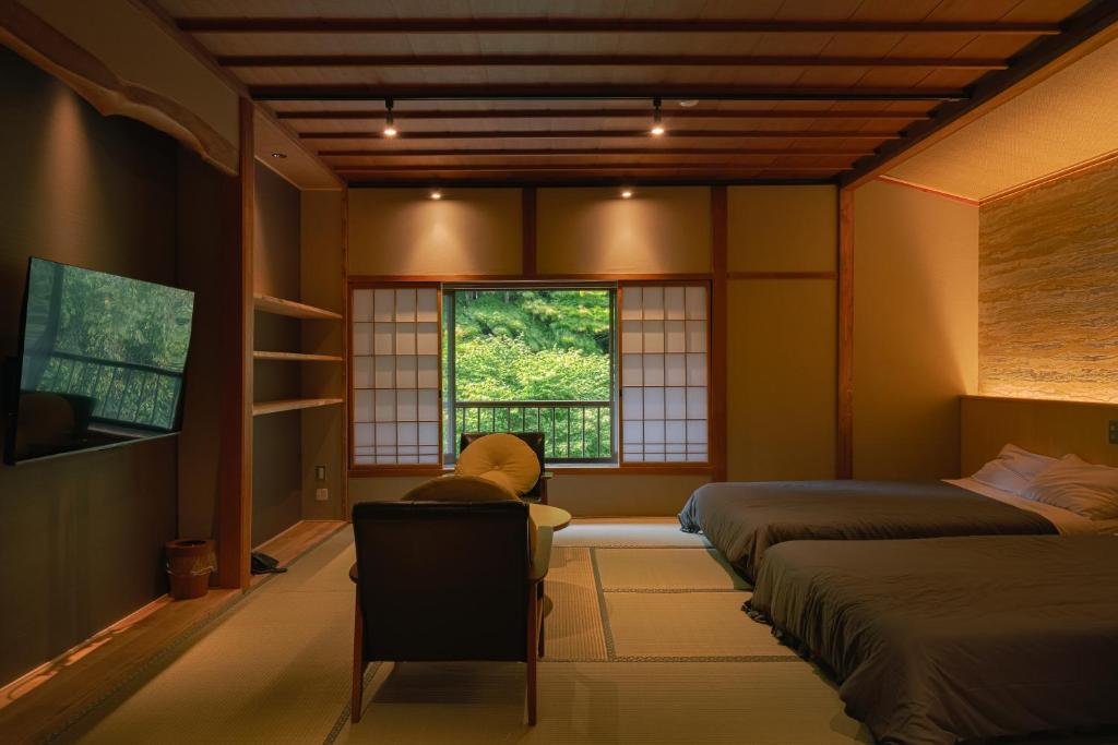 une chambre avec deux lits et une chaise et une fenêtre dans l'établissement Nukumorino-yado Komanoyu, à Kiso