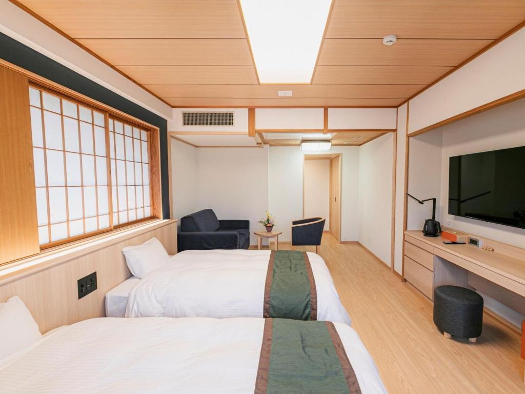 une chambre avec deux lits et une télévision à écran plat dans l'établissement Ureshino Motoyu, à Ureshino