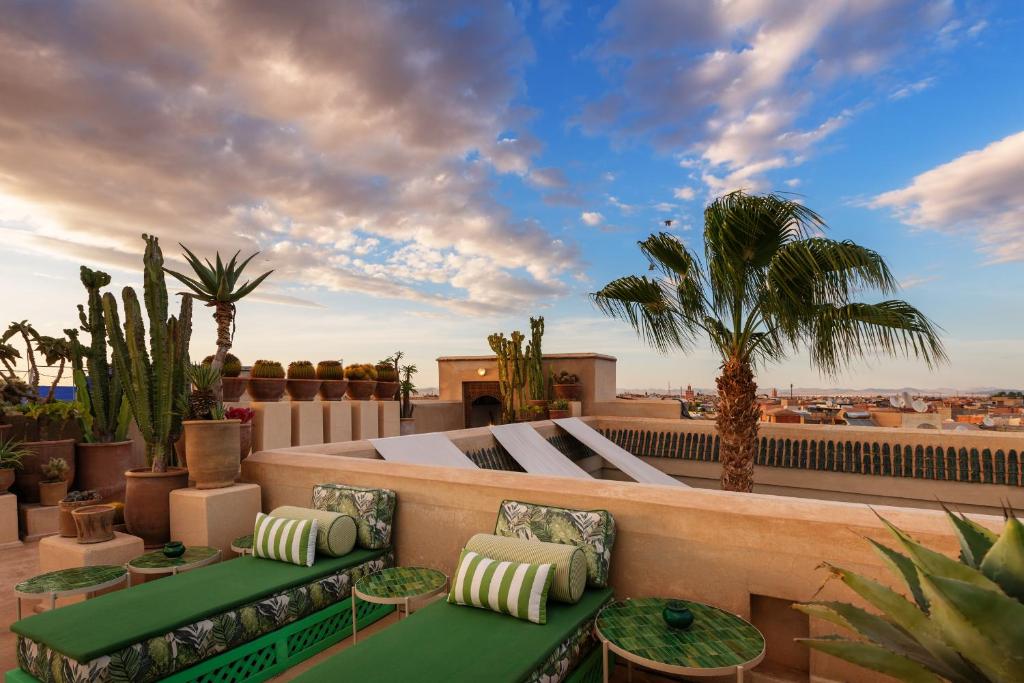 d'un toit-terrasse avec des tables vertes et des palmiers. dans l'établissement Riad Due, à Marrakech
