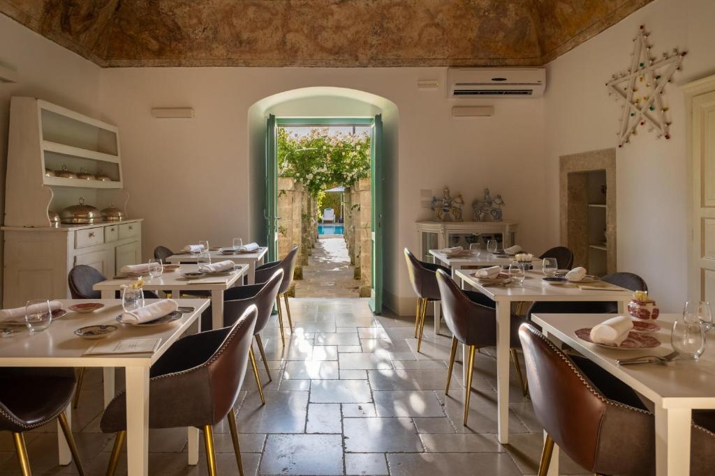 une salle à manger avec des tables et des chaises ainsi qu'une porte dans l'établissement Palazzo Ducale Venturi - Luxury Hotel & Wellness, à Minervino di Lecce