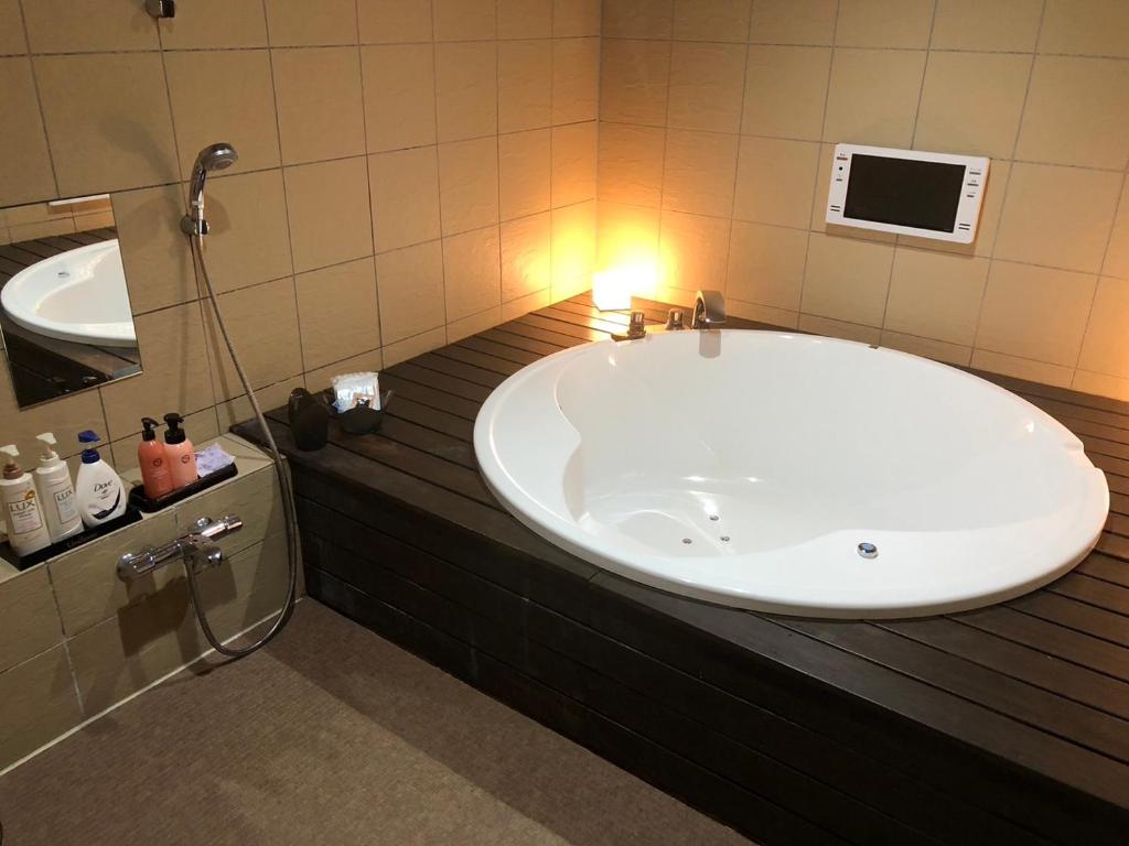 une salle de bain avec une grande baignoire et un lavabo dans l'établissement ホテルベルファス, à Koriyama