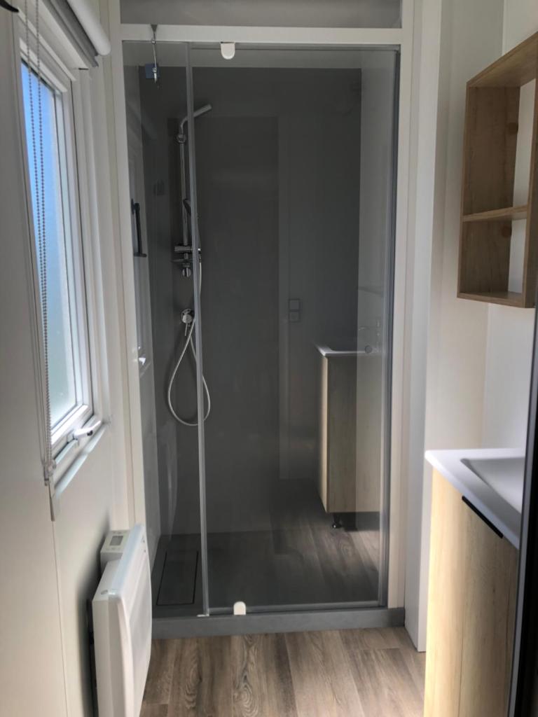 une douche avec une porte vitrée dans une salle de bain dans l'établissement Les dunes de Contis Chez Edith océan pins et détente assurée dans camping 4 étoiles, à Saint-Julien-en-Born