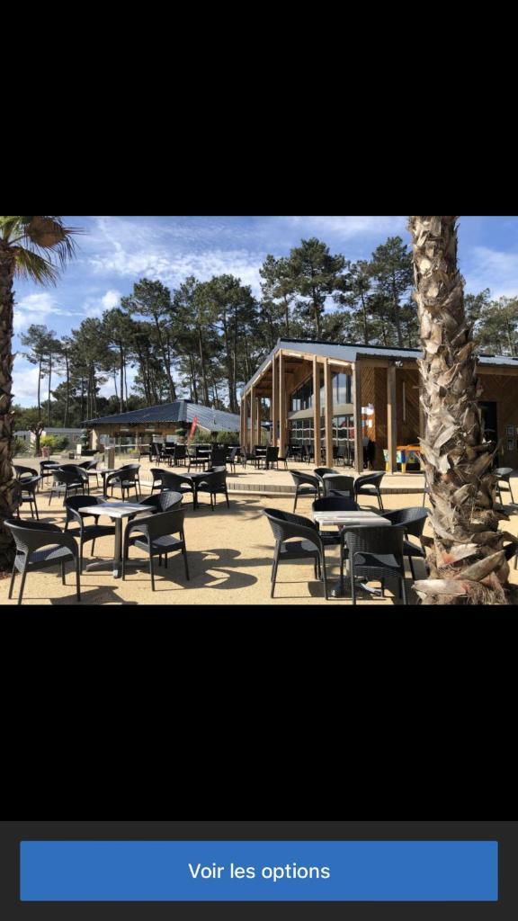 un groupe de tables et de chaises devant un bâtiment dans l'établissement Les dunes de Contis Chez Edith océan pins et détente assurée dans camping 4 étoiles, à Saint-Julien-en-Born