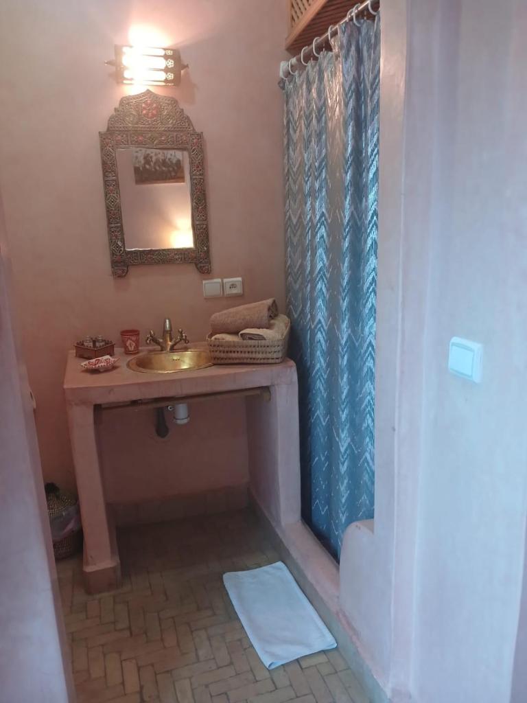 une salle de bain avec un lavabo et une douche avec un miroir dans l'établissement Riad Dantella, à Marrakech