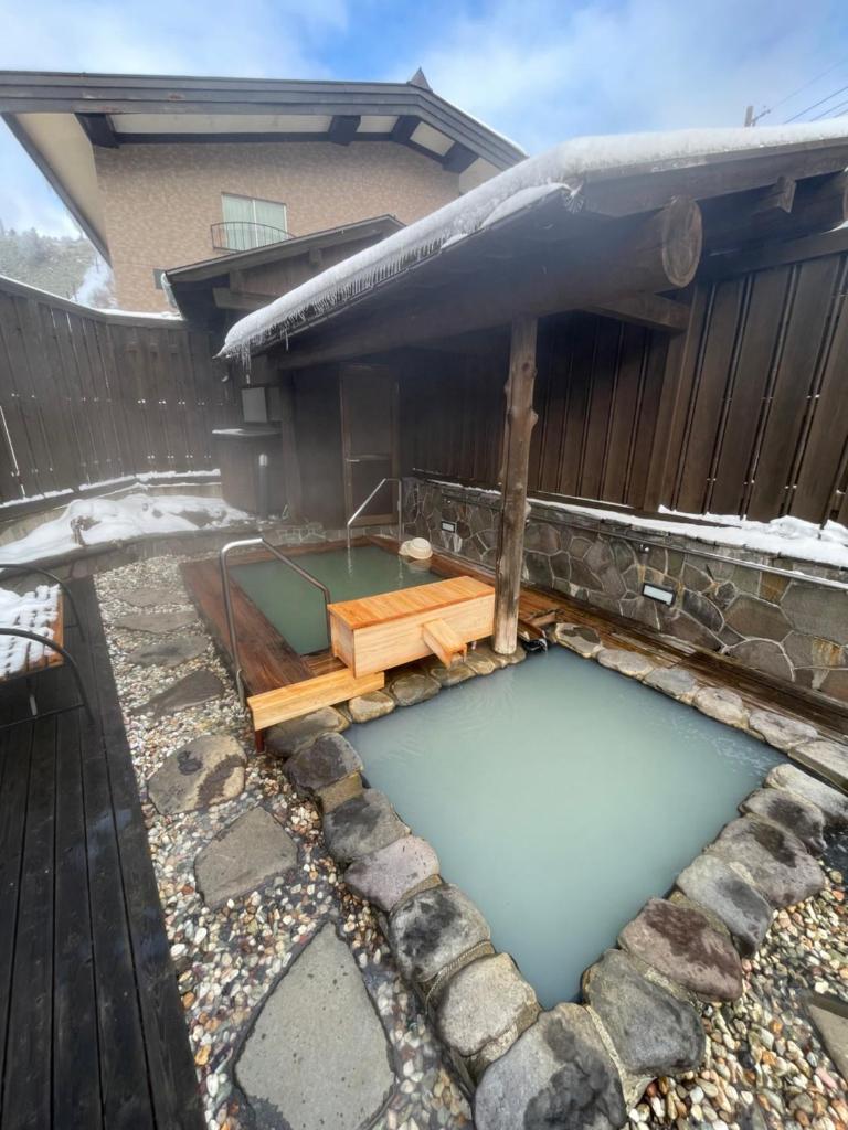 une piscine d'eau en face d'une maison dans l'établissement Hotel & Onsen 2307 Shigakogen, à Yamanouchi
