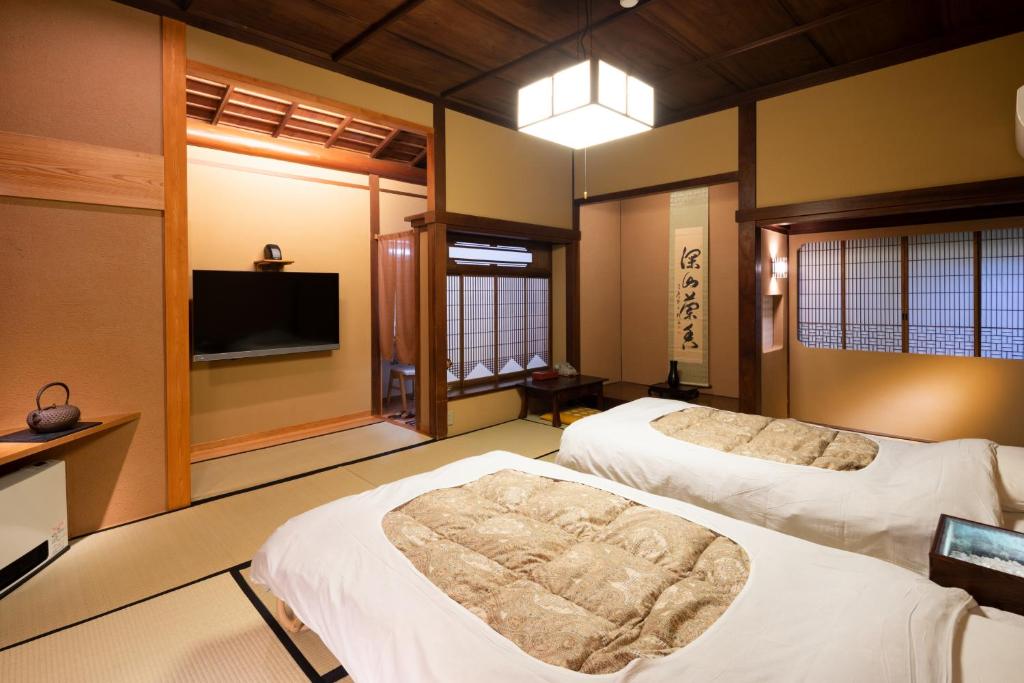 une chambre avec deux lits et une télévision à écran plat dans l'établissement Gensen Uenoya, à Yugawara 37 autres photos