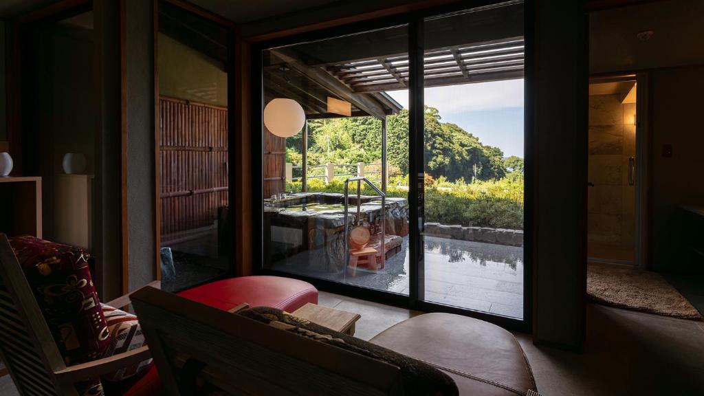 - un salon avec une fenêtre offrant une vue sur une baignoire dans l'établissement Isaribi (No Children), à Higashiizu