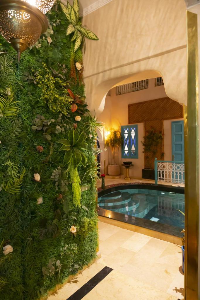 une grande piscine intérieure avec un mur vert dans l'établissement Riad La Rose Orientale Marrakech, à Marrakech