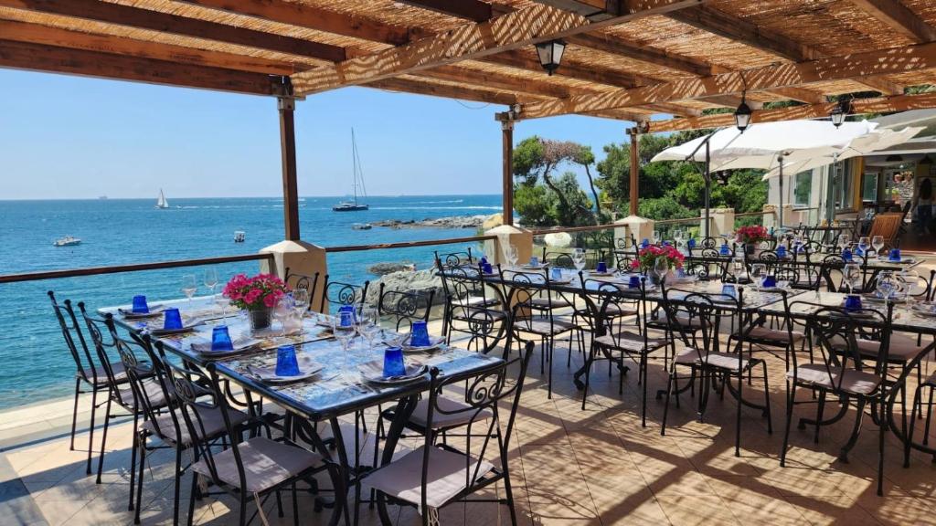 un groupe de tables et de chaises avec l'océan en arrière-plan dans l'établissement Locanda Il Senatore, à Fiascherino